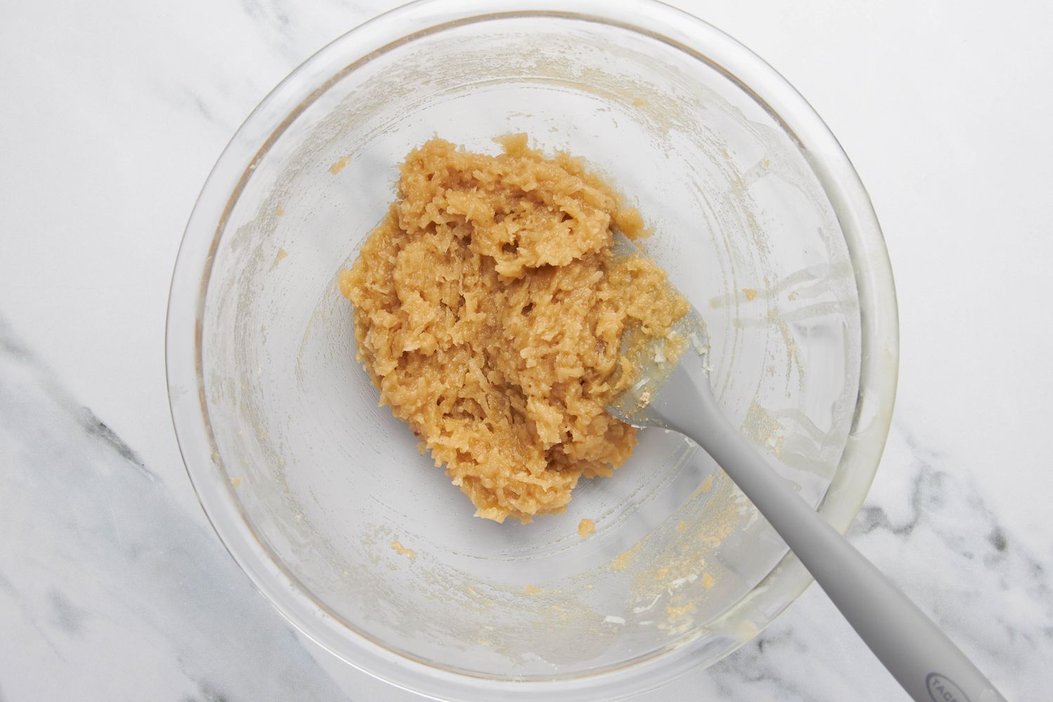 Shredded coconut topping ingredients mixed together in a bowl using a spatula 