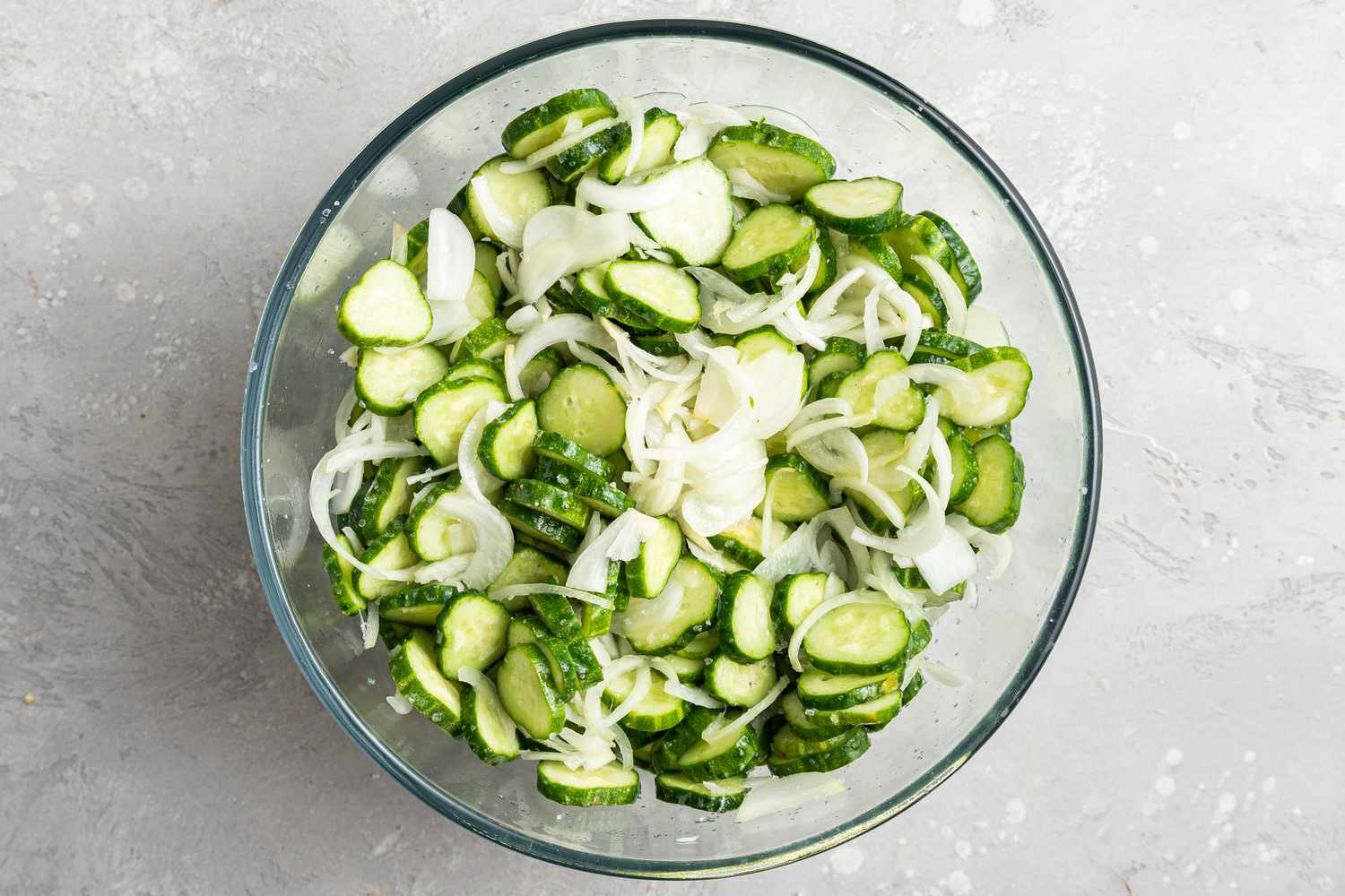Cucumbers and onions salted in a glass bowl