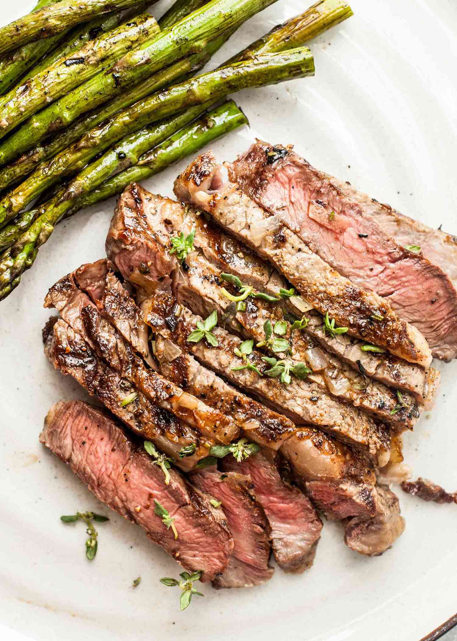 Grilled steak sliced and served on a platter with asapragus