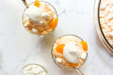 Orange creamsicle salad served in small glass bowls topped with whipped cream and marshmallows