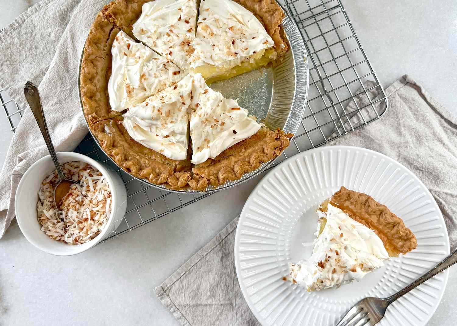 Buttermilk coconut pie served in slices on a plate and in a pan, on a wire rack with a side dish of coconut pieces