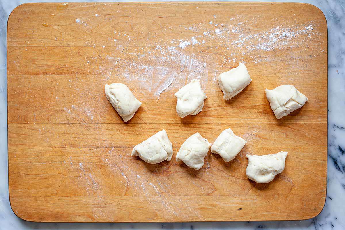 Dough for easy homemade flour tortillas is separated into eight equal pieces on a wooden cutting board.