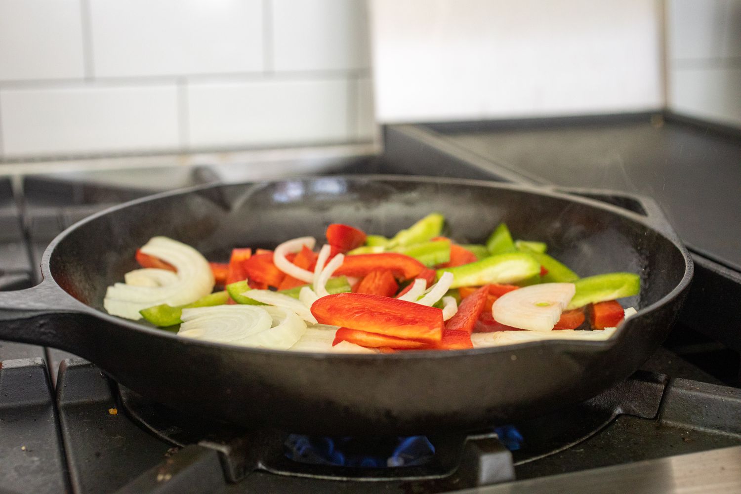 Peppers cooking in a pan to make an authentic Philly cheesesteak recipe