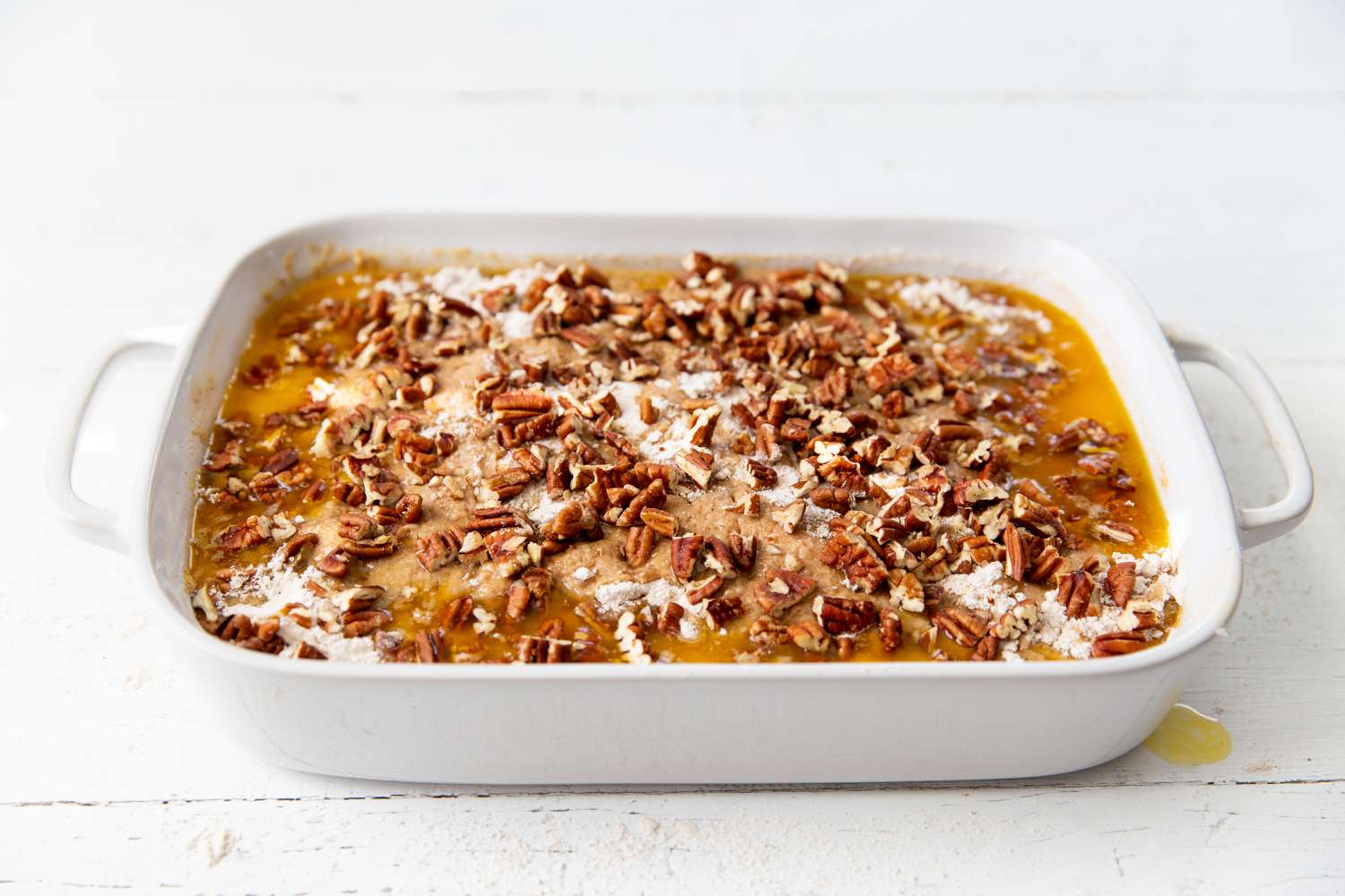 chopped pecans sprinkled on the top of the mixture in the baking dish for Pumpkin Dump Cake
