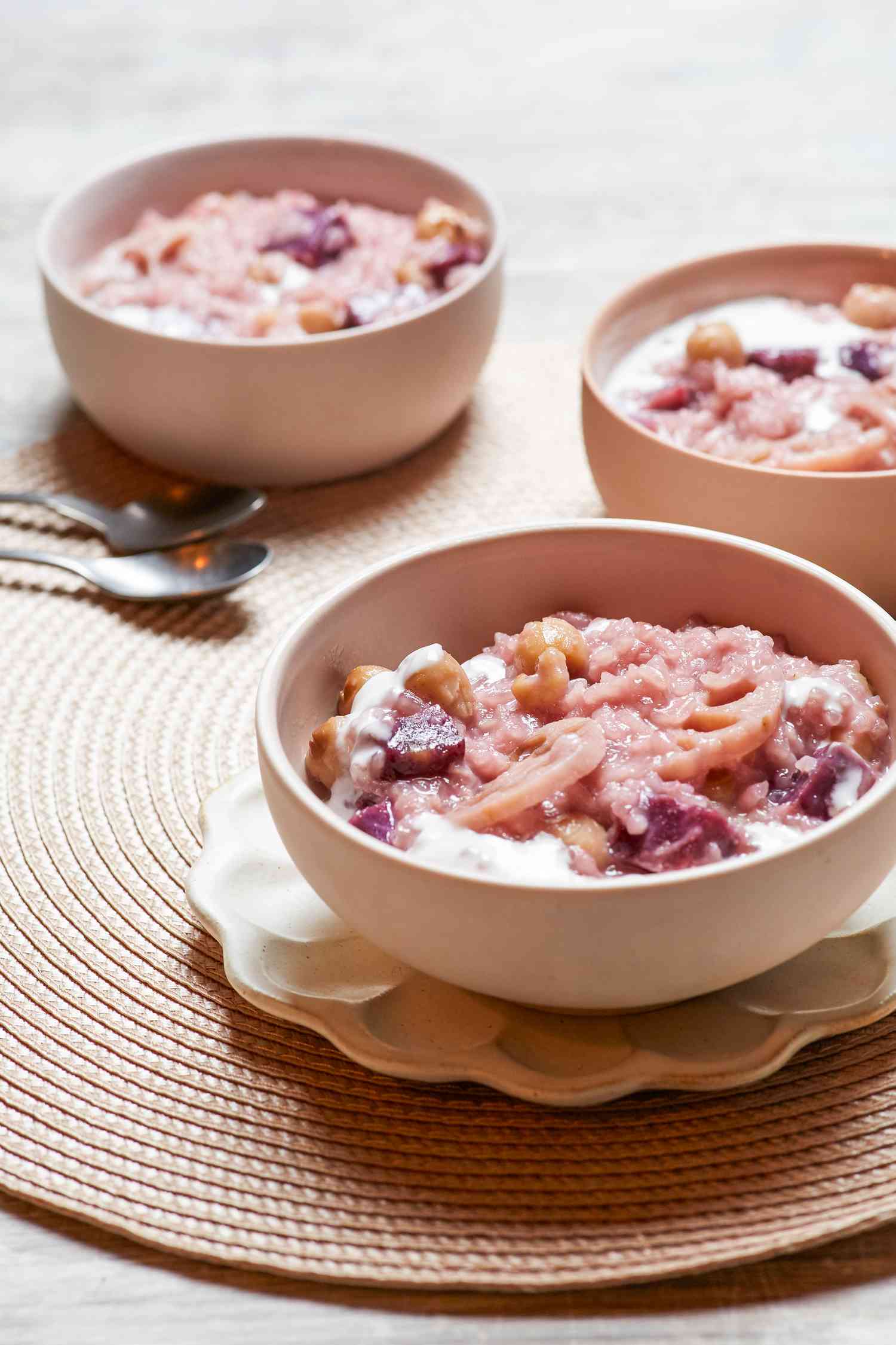 Coconut rice pudding with lotus and sweet potato served in a bowl with a spoon.