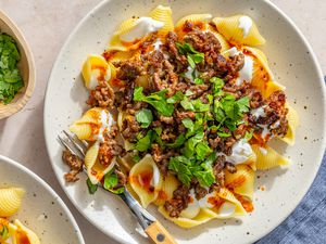 A plate of Turkish pasta topped with ground meat, yogurt, and fresh herbs