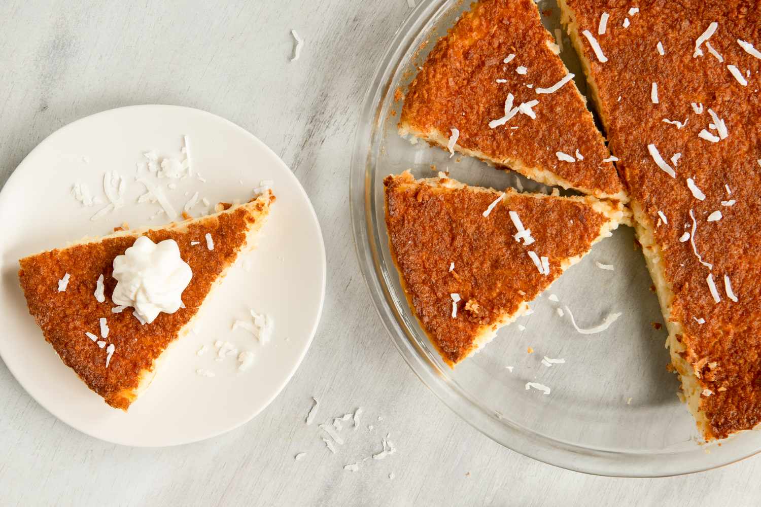 A sliced coconut pie with a piece served on a plate