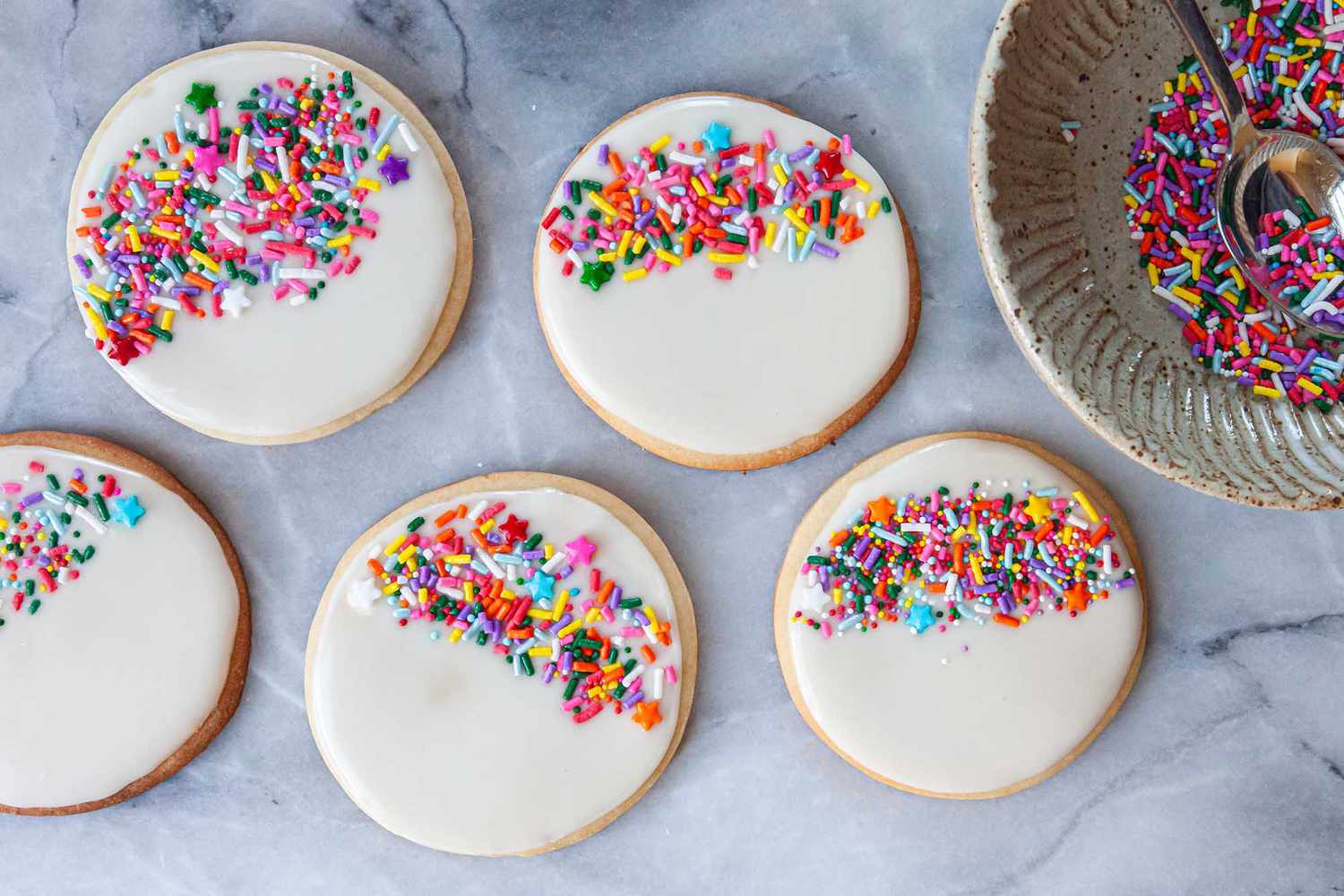 Round sugar cookies decorated with Royal icing for sugar cookies and rainbow sprinkles.