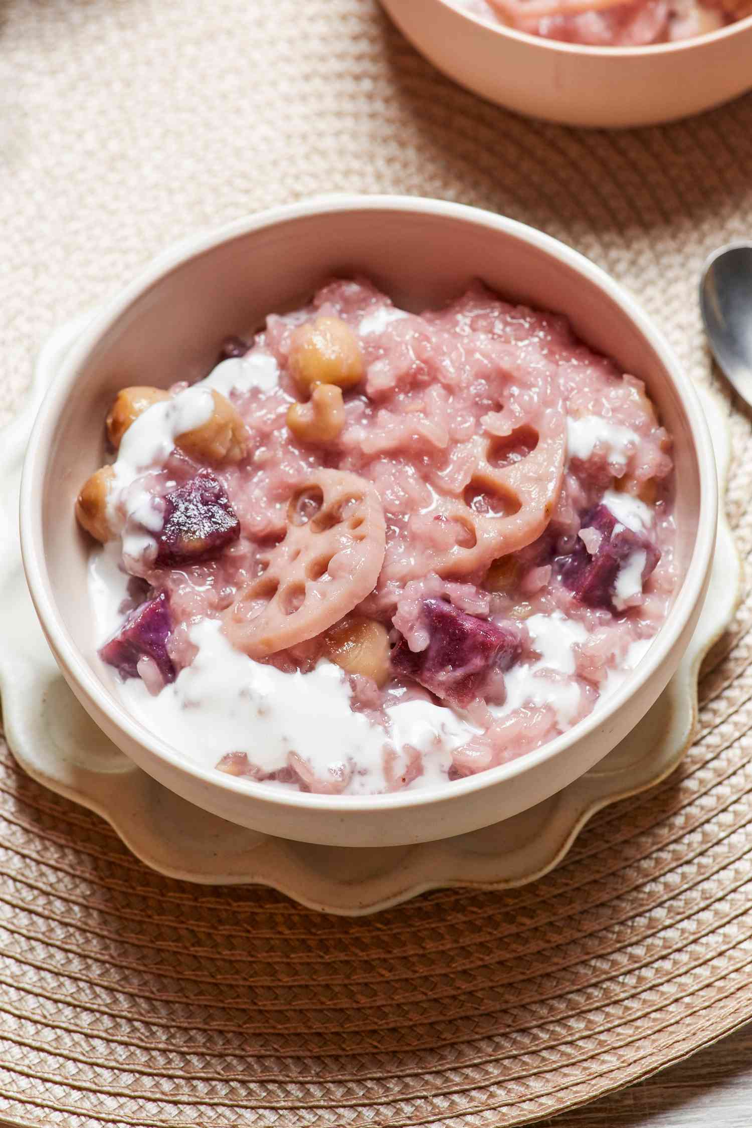 Coconut rice pudding with lotus and sweet potato served in a bowl with a spoon.