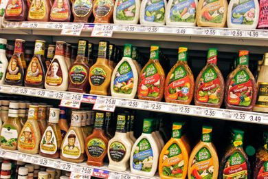 A supermarket shelf displaying various salad dressings of different brands and varieties