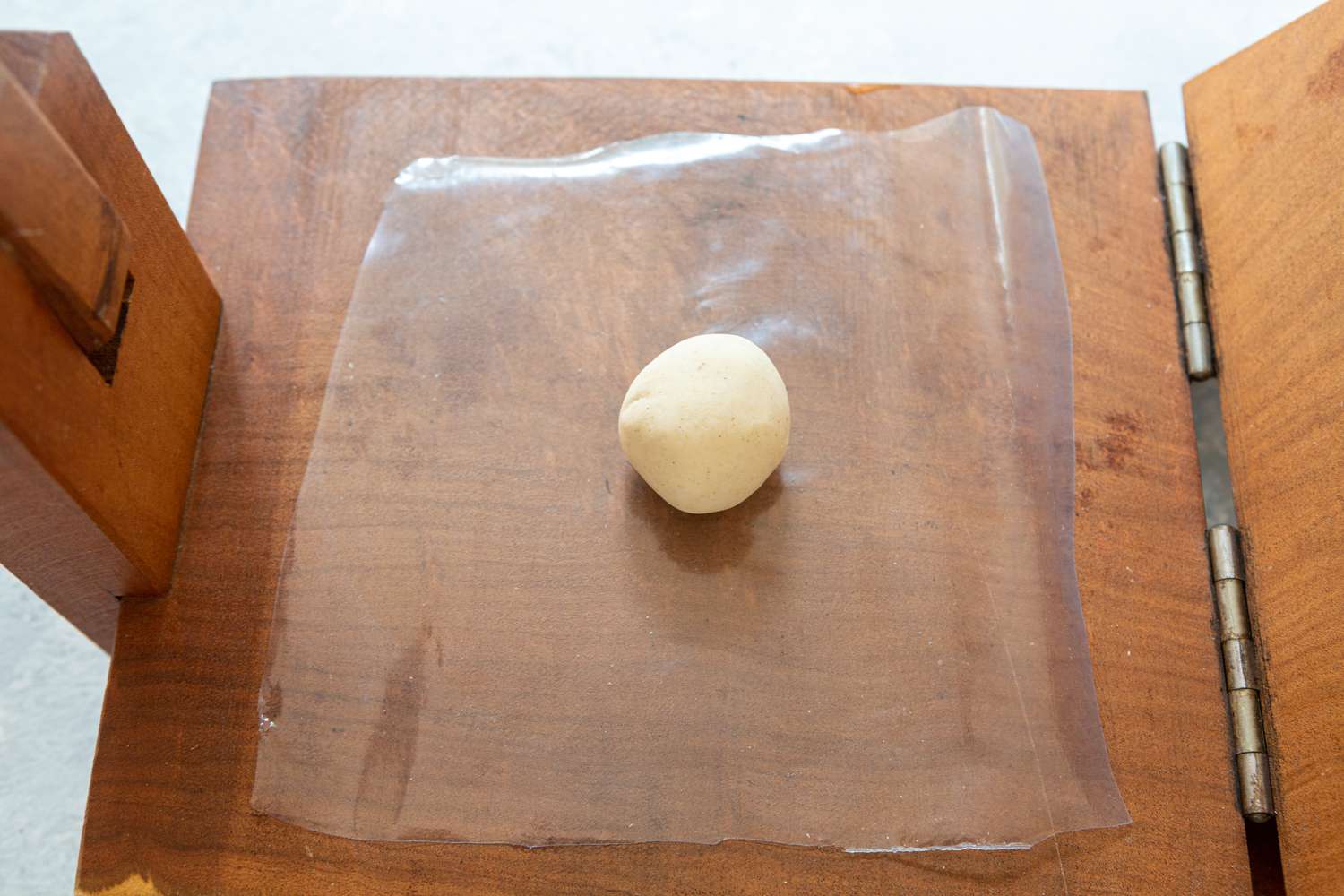 A dough ball in a wooden tortilla press 