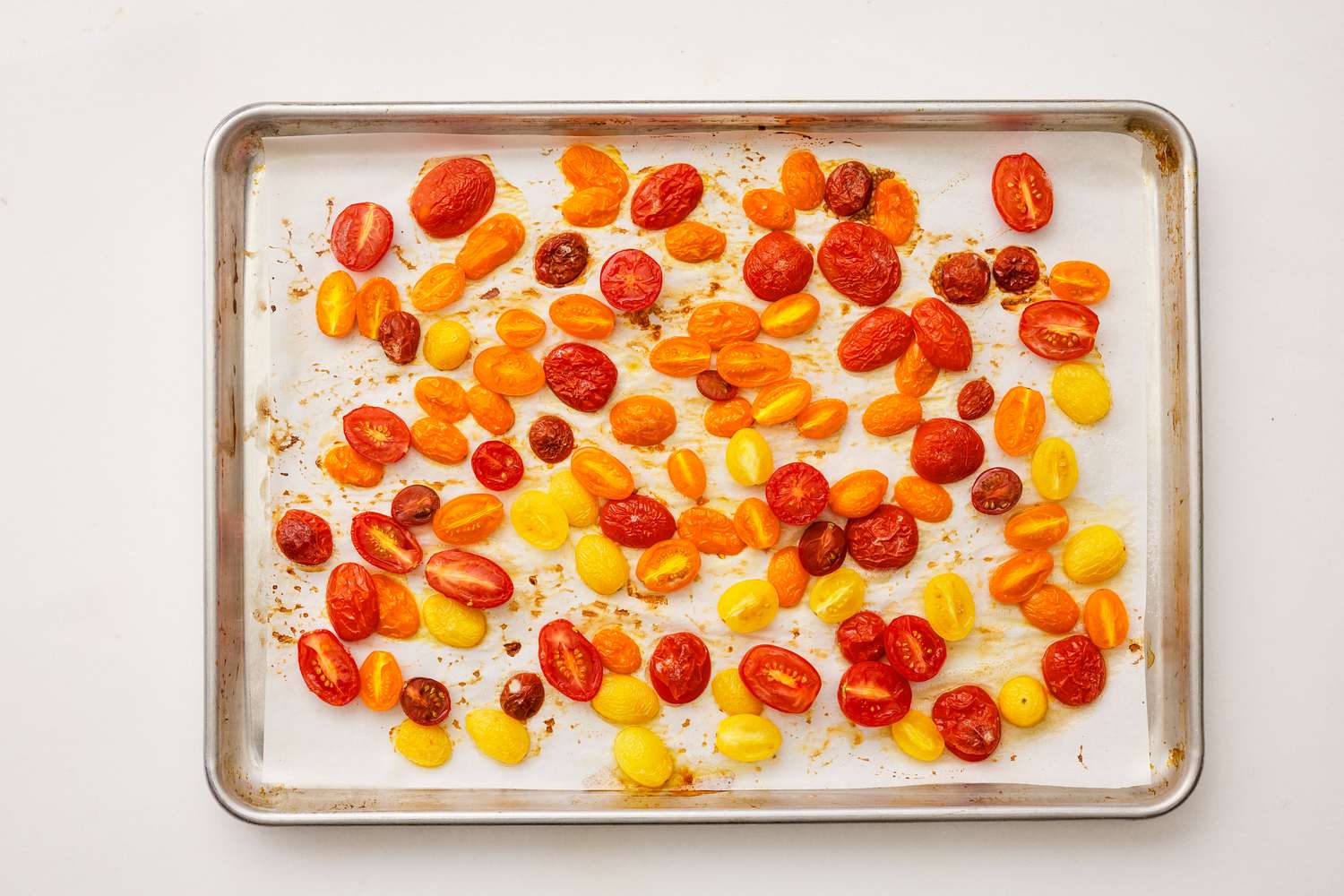 halved cherry tomatoes on a parchment paper lined baking sheet for tomato pie dip recipe