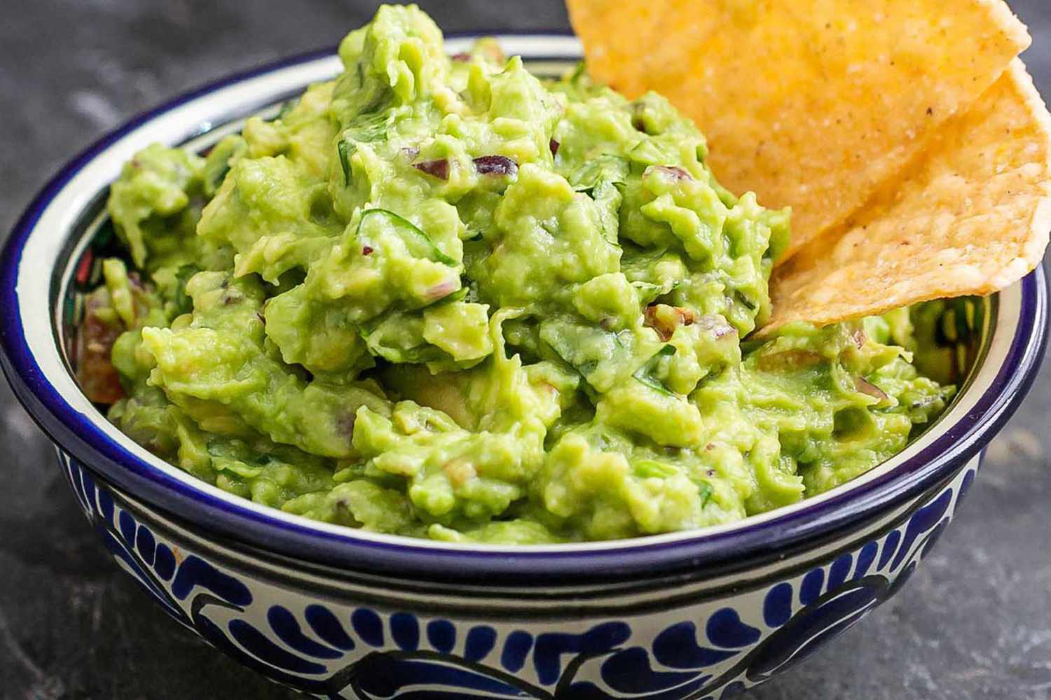 A bowl of guacamole with tortilla chips