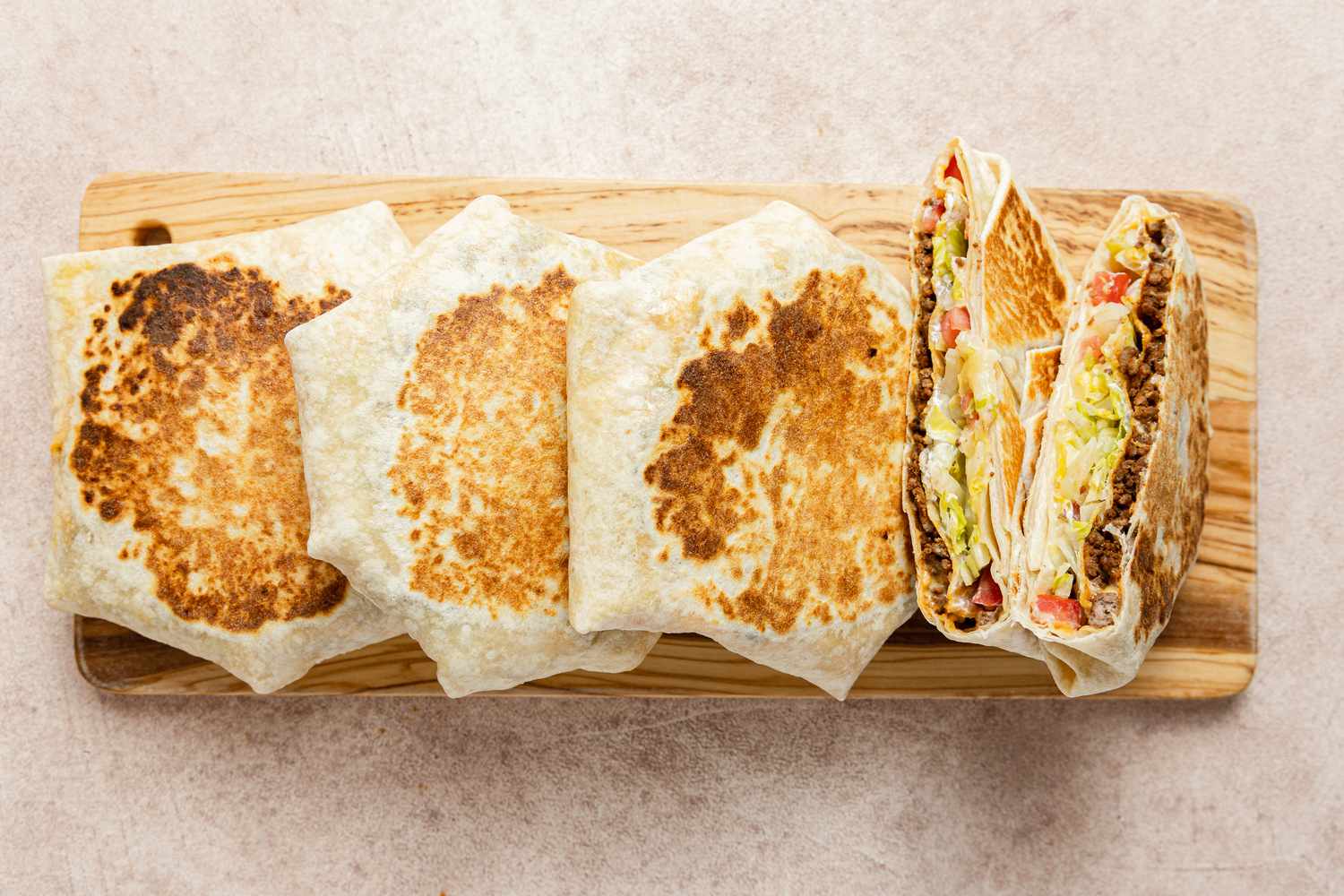 Copycat Crunchwraps on a Wooden Cutting Board with One Cut in Half