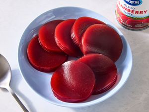 Slices of canned cranberry sauce on a plate next to a spoon and the can