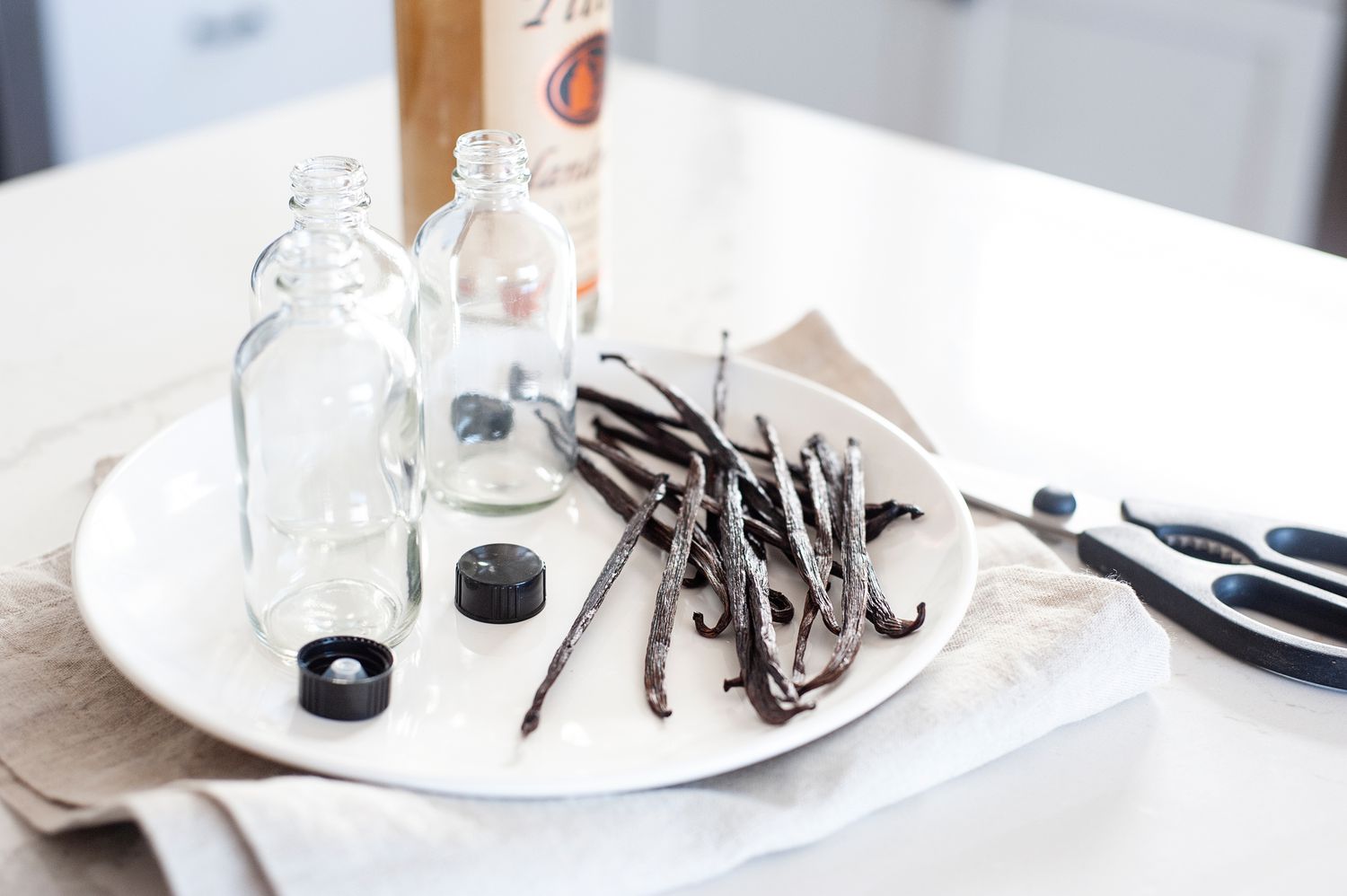 Diy vanilla extract with bottles and vanilla beans on a platter.