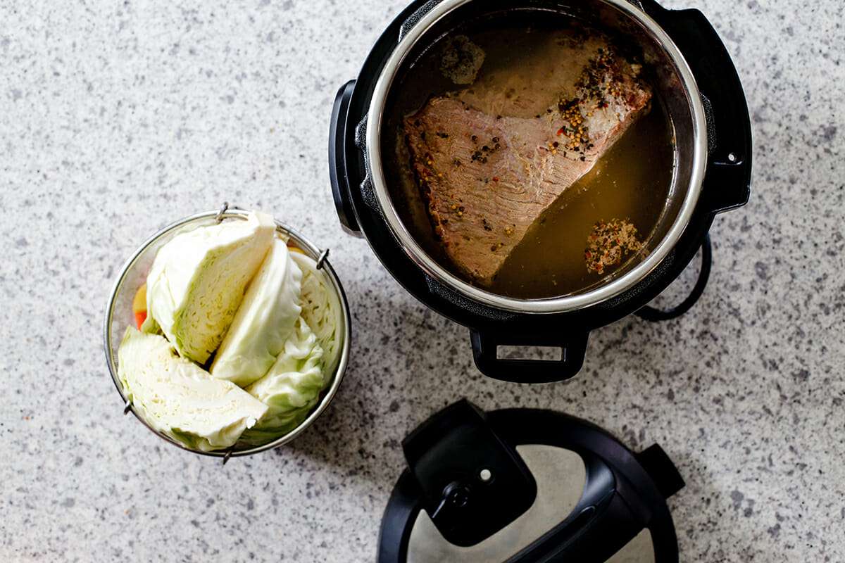 Easy Corned Beef and Cabbage - instant pot with corned beef inside and sliced cabbage on the side