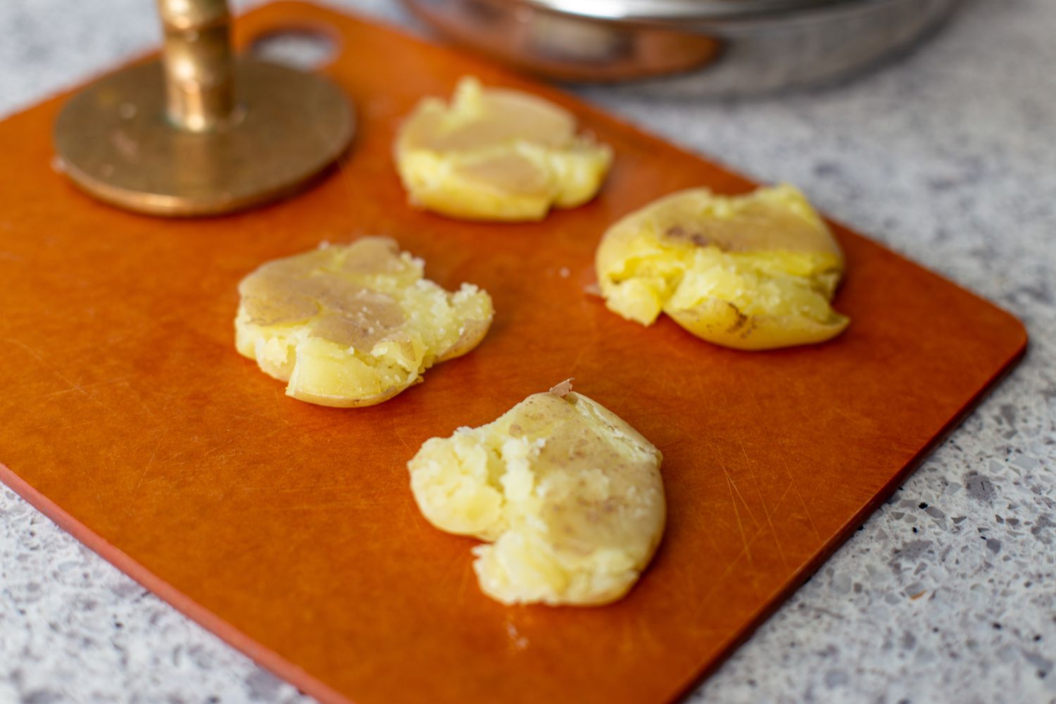 Smashed potatoes on a cutting board for an easy appetizer.