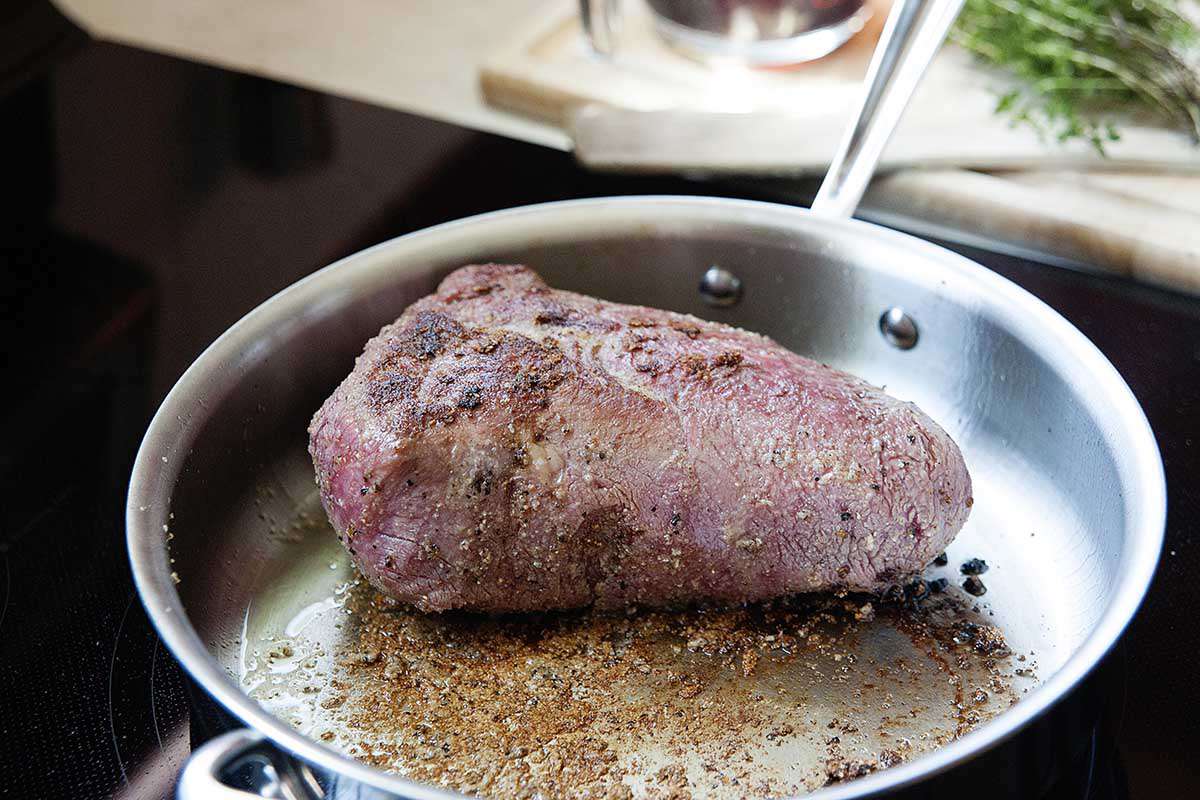 Searing a chuck roas in a sliver skillet with lots of fond on the bottom.