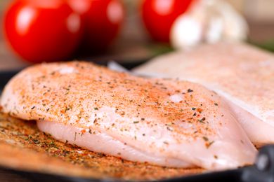 Sideview of a seasoned raw chicken breast