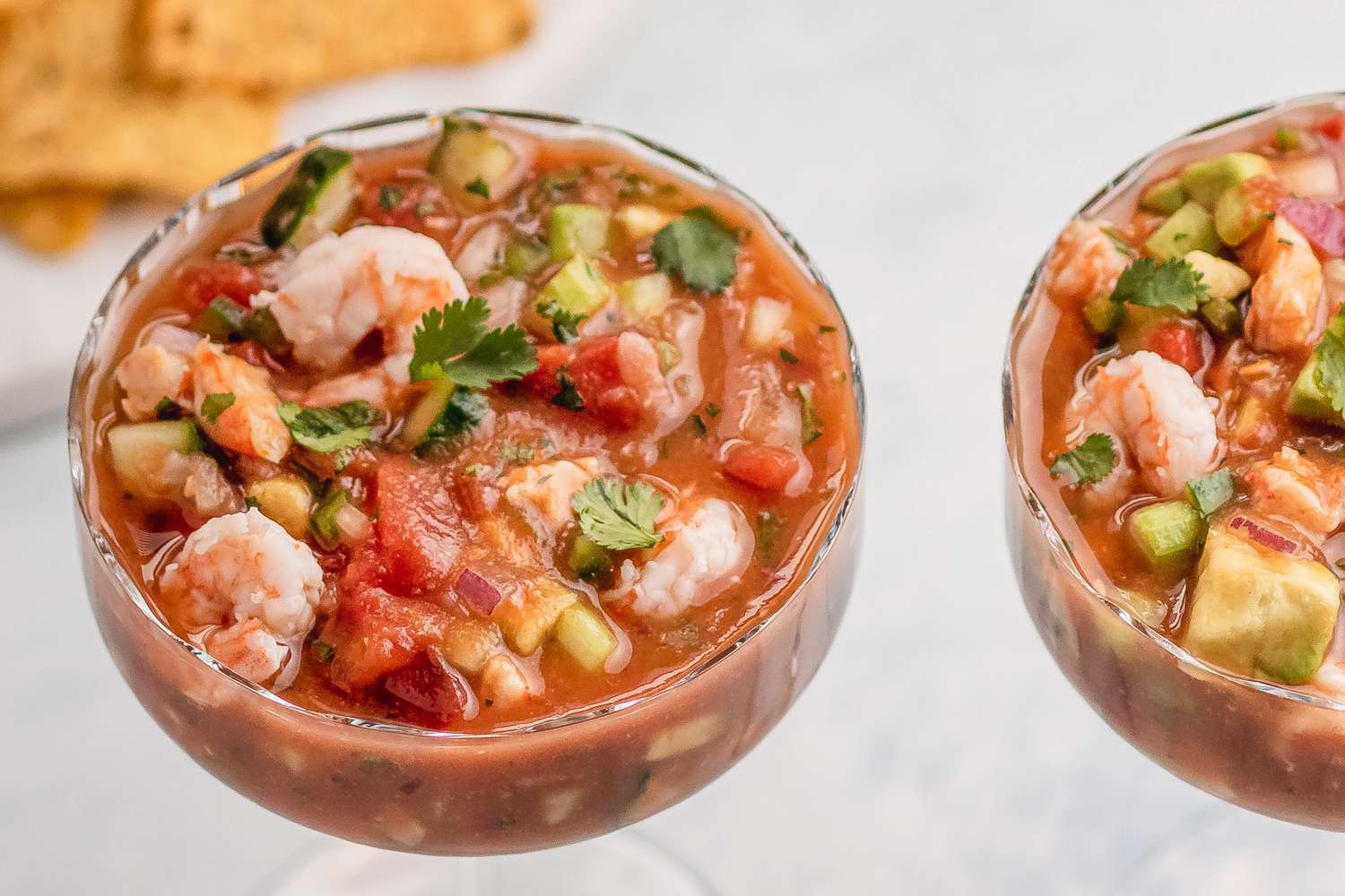 Overhead view of two stemmed glasses full of Mexican shrimp cocktail