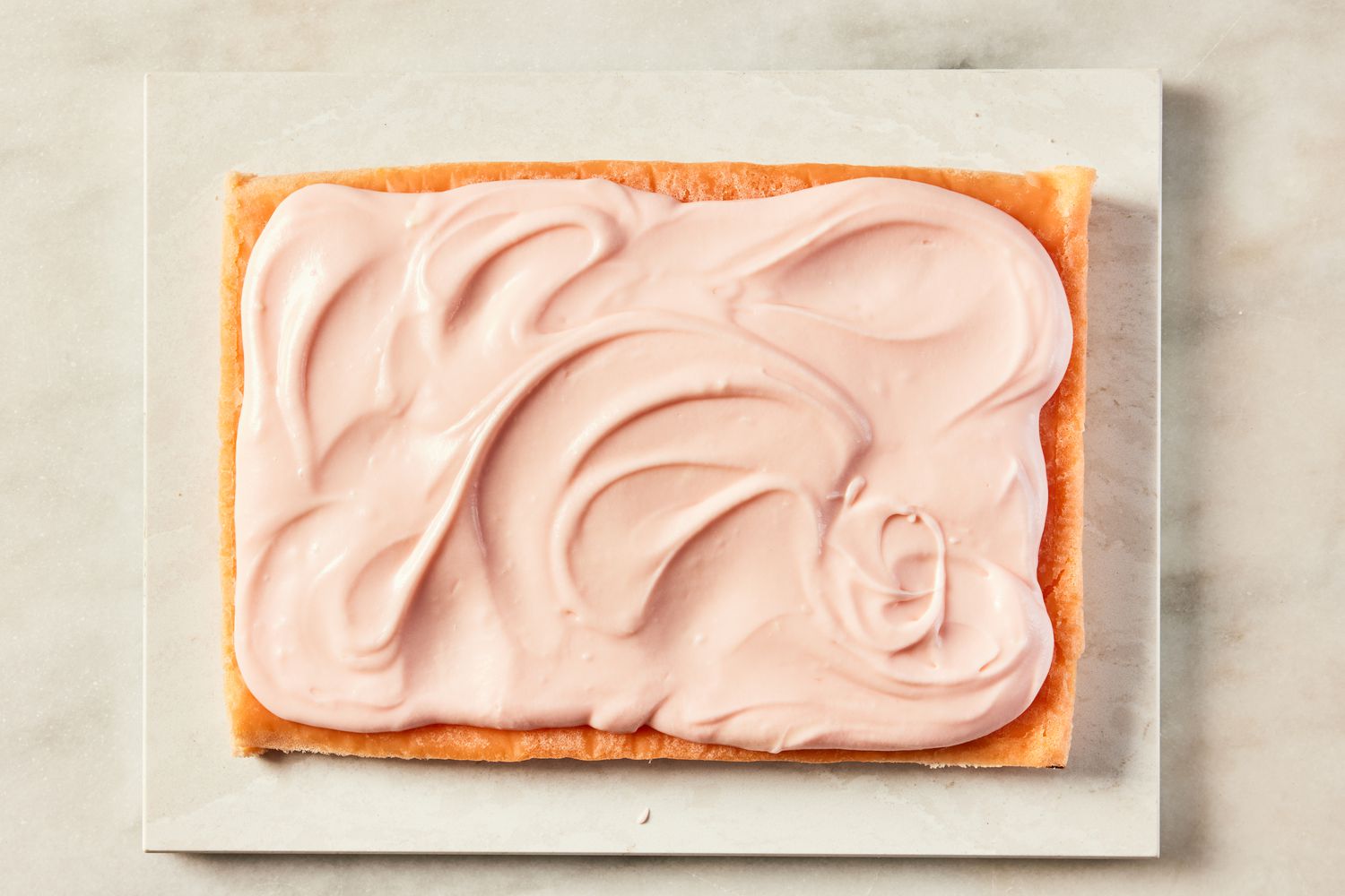 icing spread onto pink lemonade cake for pink lemonade cake recipe