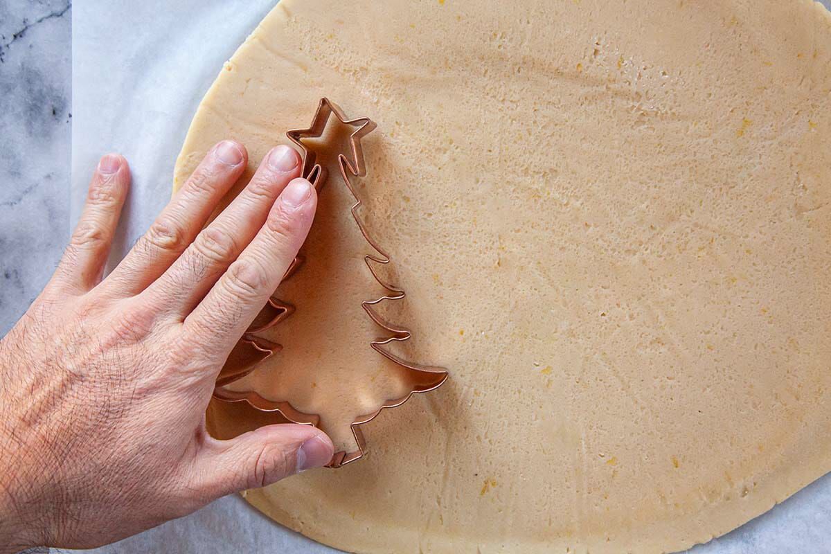 Christmas tree cookie cutter pressed into rolled out dough to make Sugar Cookies.