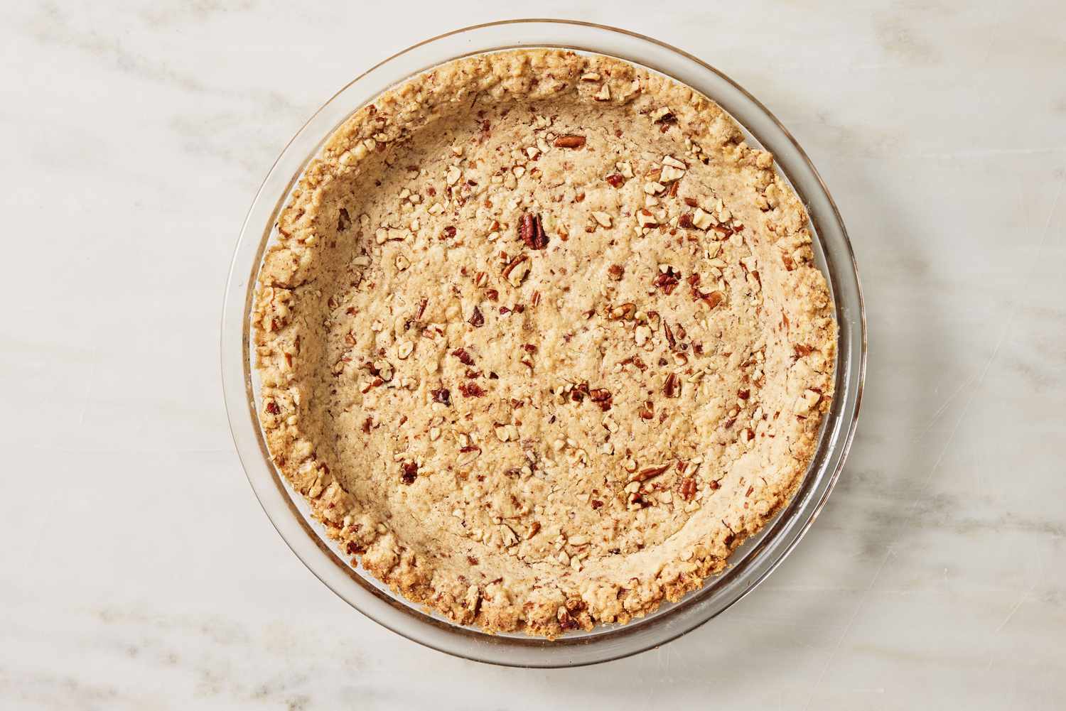 overhead view of baked pecan crust in a pie plate for Arkansas Possum Pie recipe