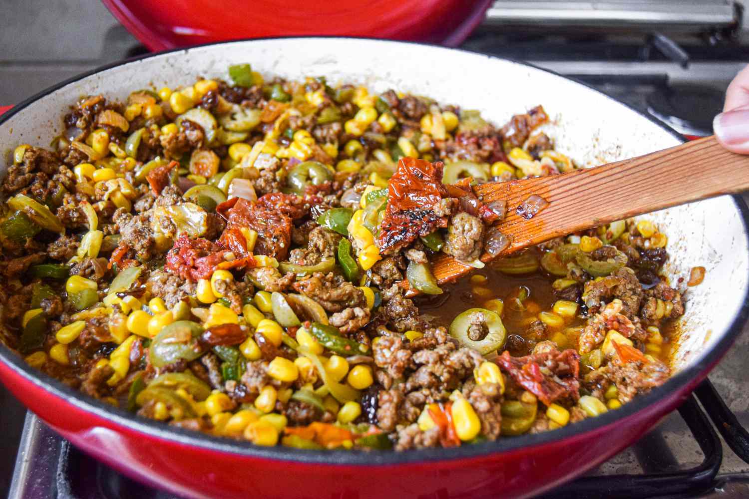 Tamale pie ingredients being stirred with a spoon and cooking in a pan
