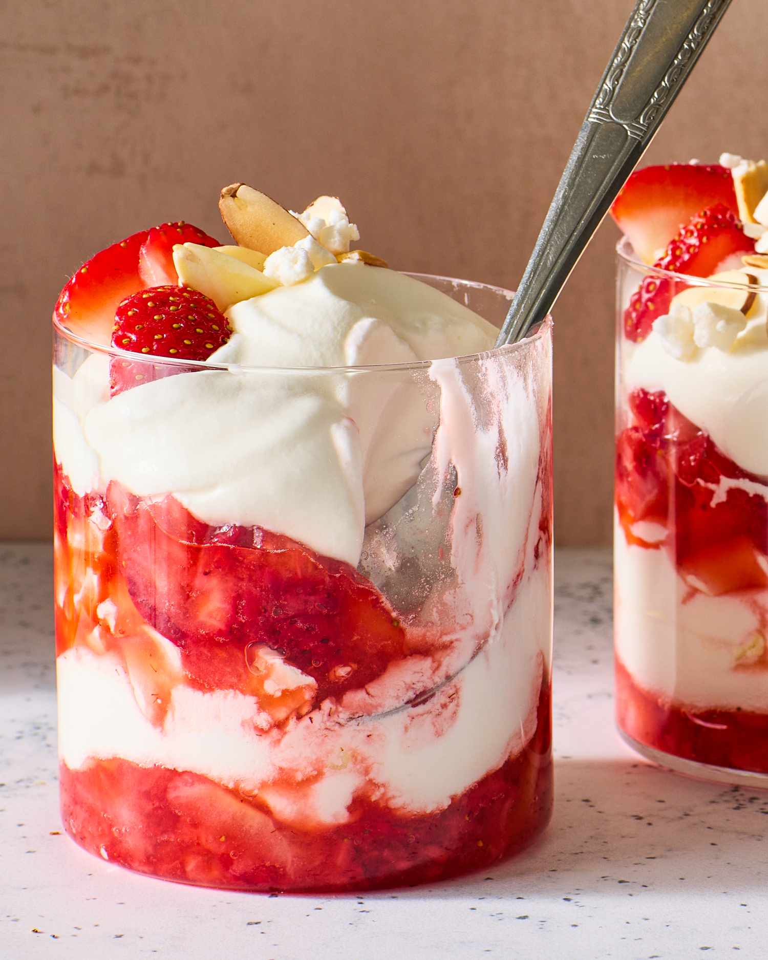 Dessert cups with layers of strawberries, whipped cream, and meringue pieces