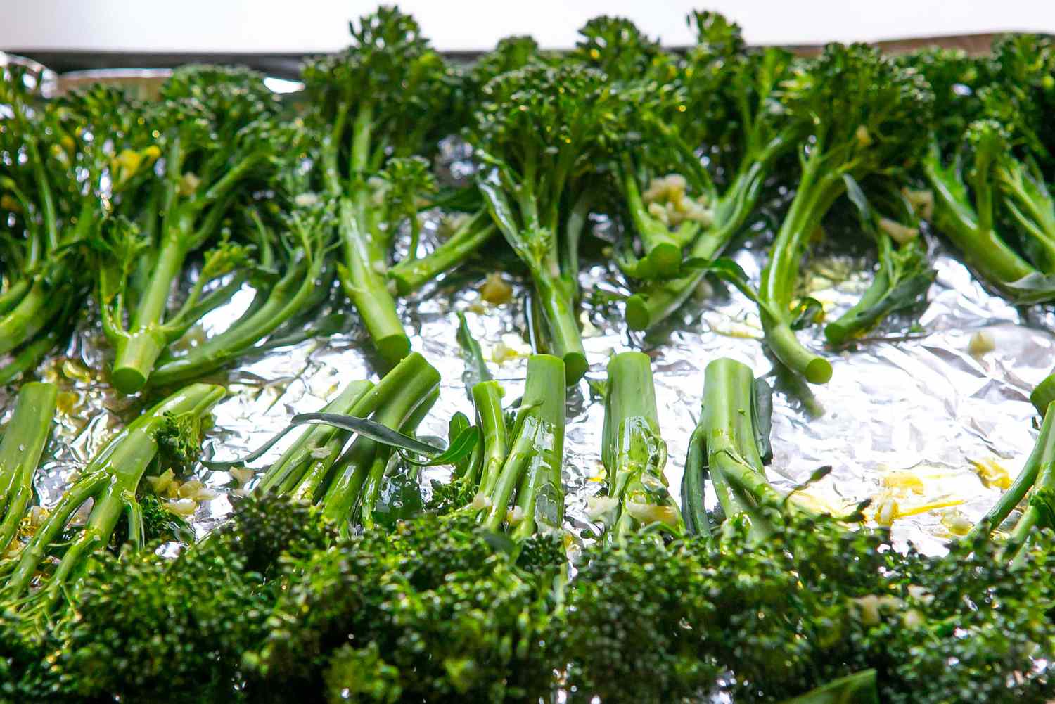 A baking sheet filled with broccolini to show how to cook broccolini.