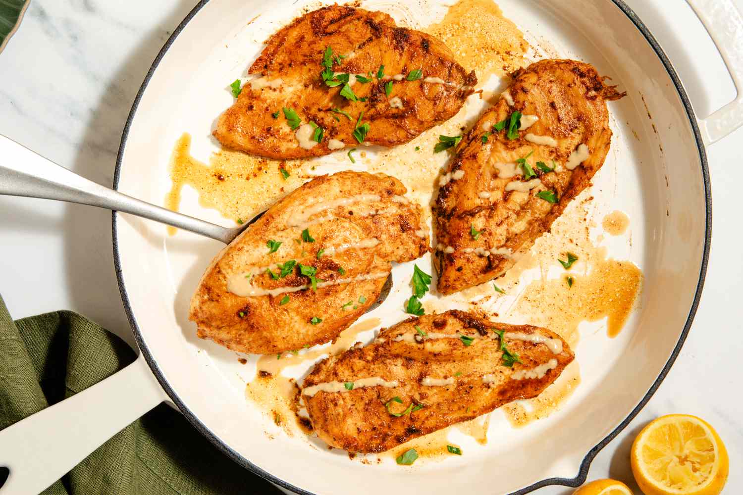 Overhead view of Garlic-Tahini chicken breast cutlets cooking in a white skillet