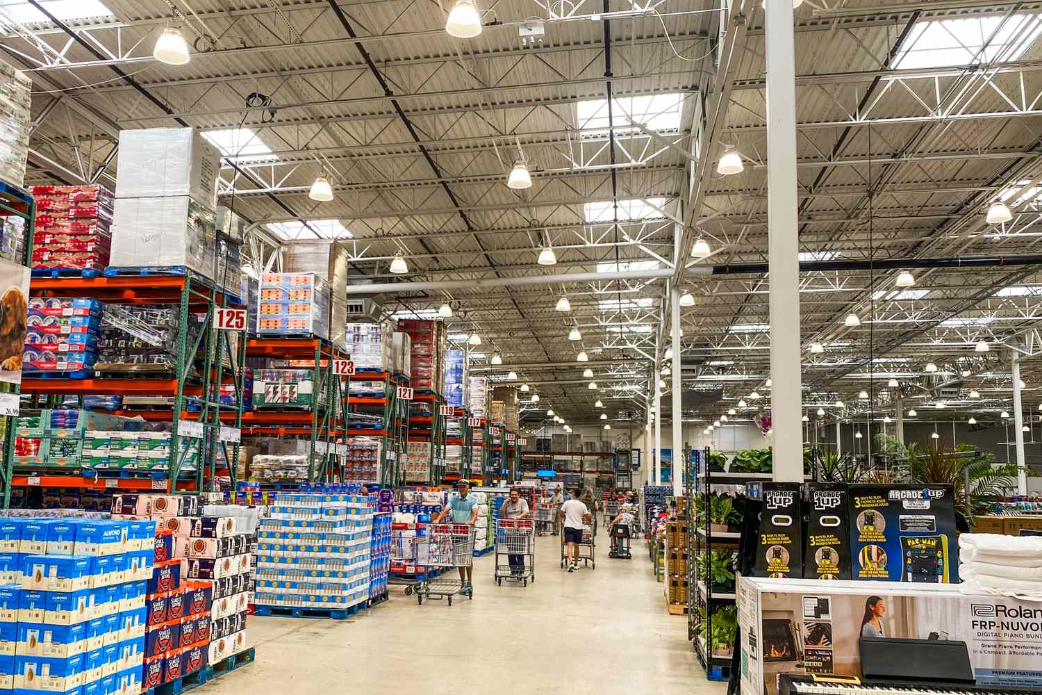 A store aisle with shelves stocked with products and shoppers in the distance likely in a Costco warehouse