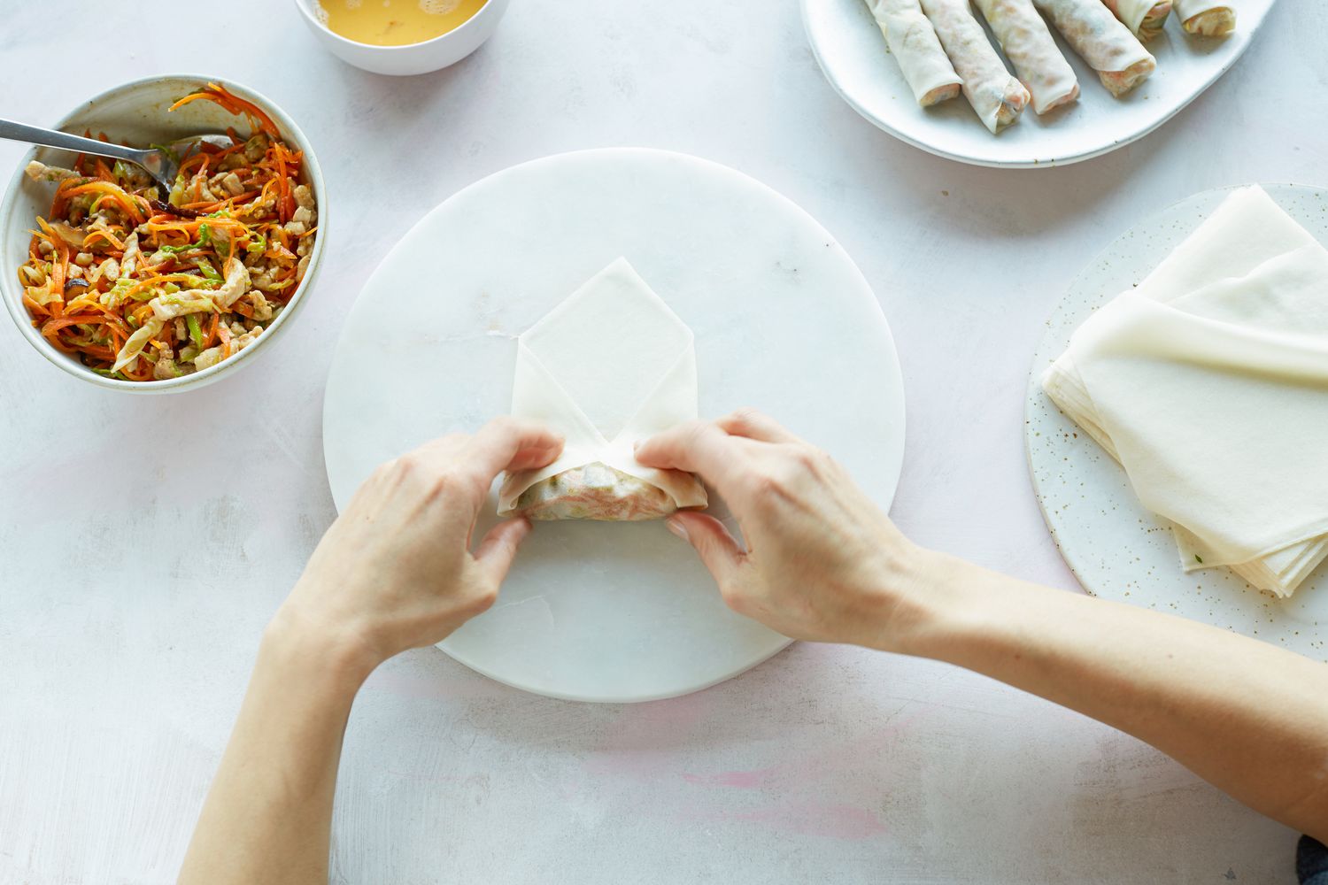 Hands showing how to roll a spring roll.
