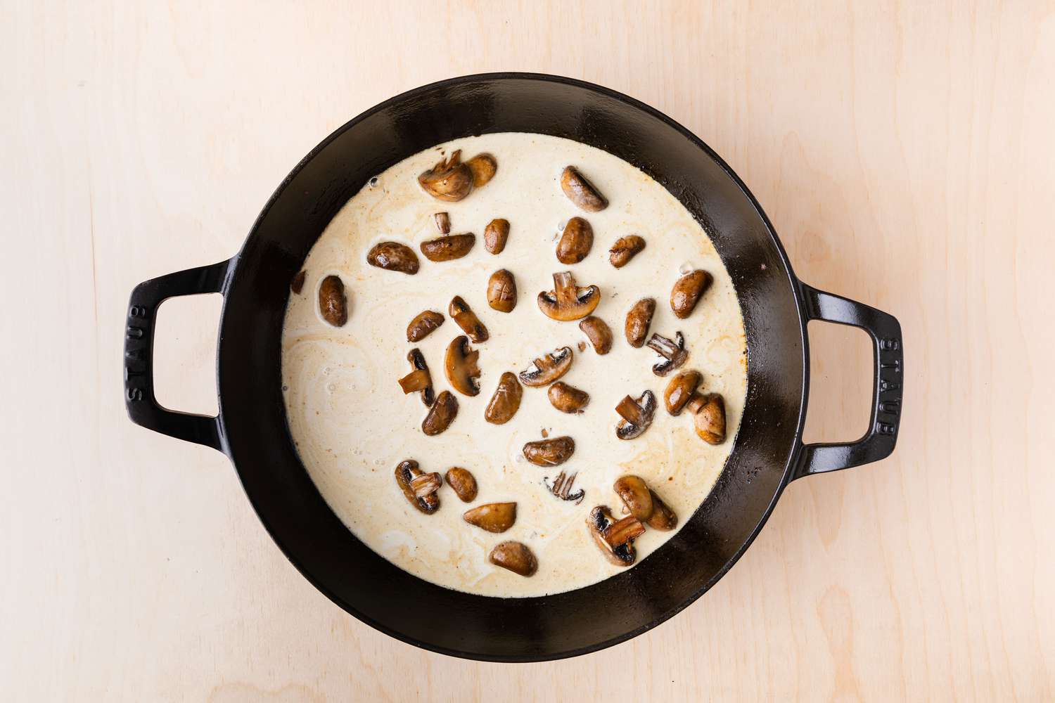 creamy sauce with mushrooms cooking in large cast iron skillet for Chicken Supreme
