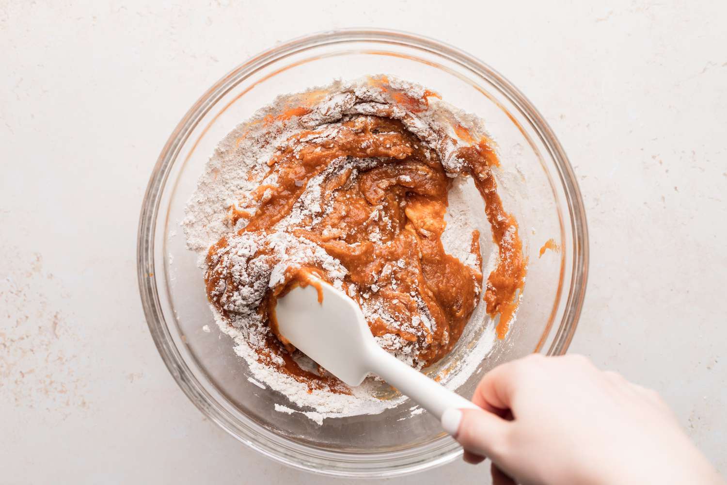 Folding wet ingredients in to dry to make classic pumpkin muffins.