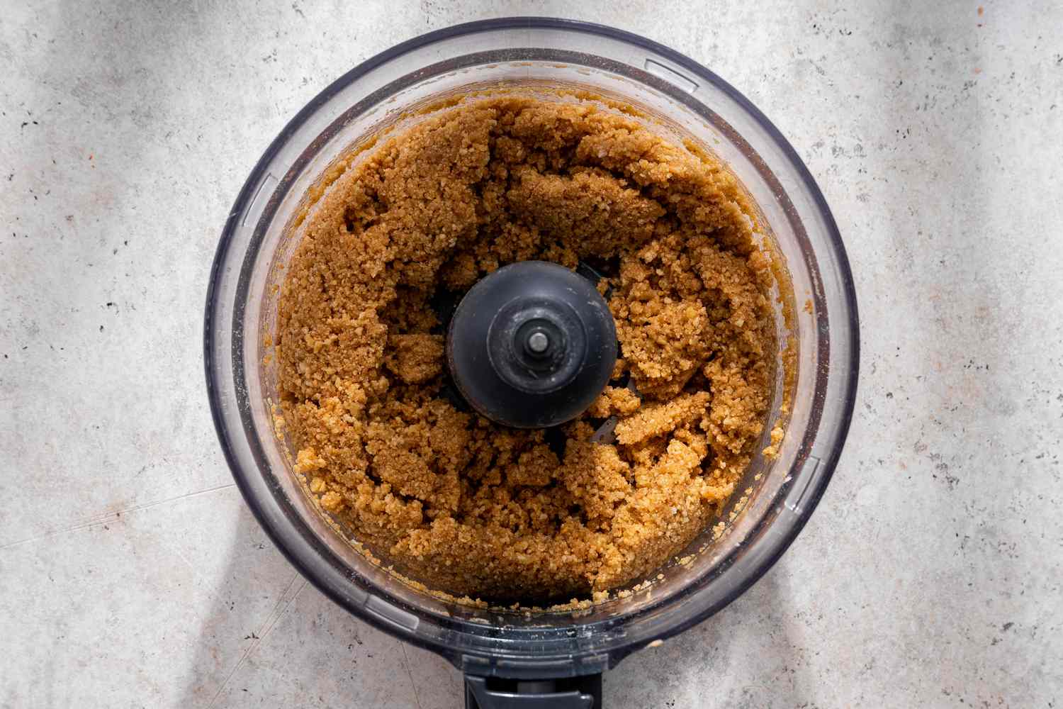 Graham cracker crumbs in food processor after mixed with melted butter, sugar, and salt for no-bake pumpkin pie recipe
