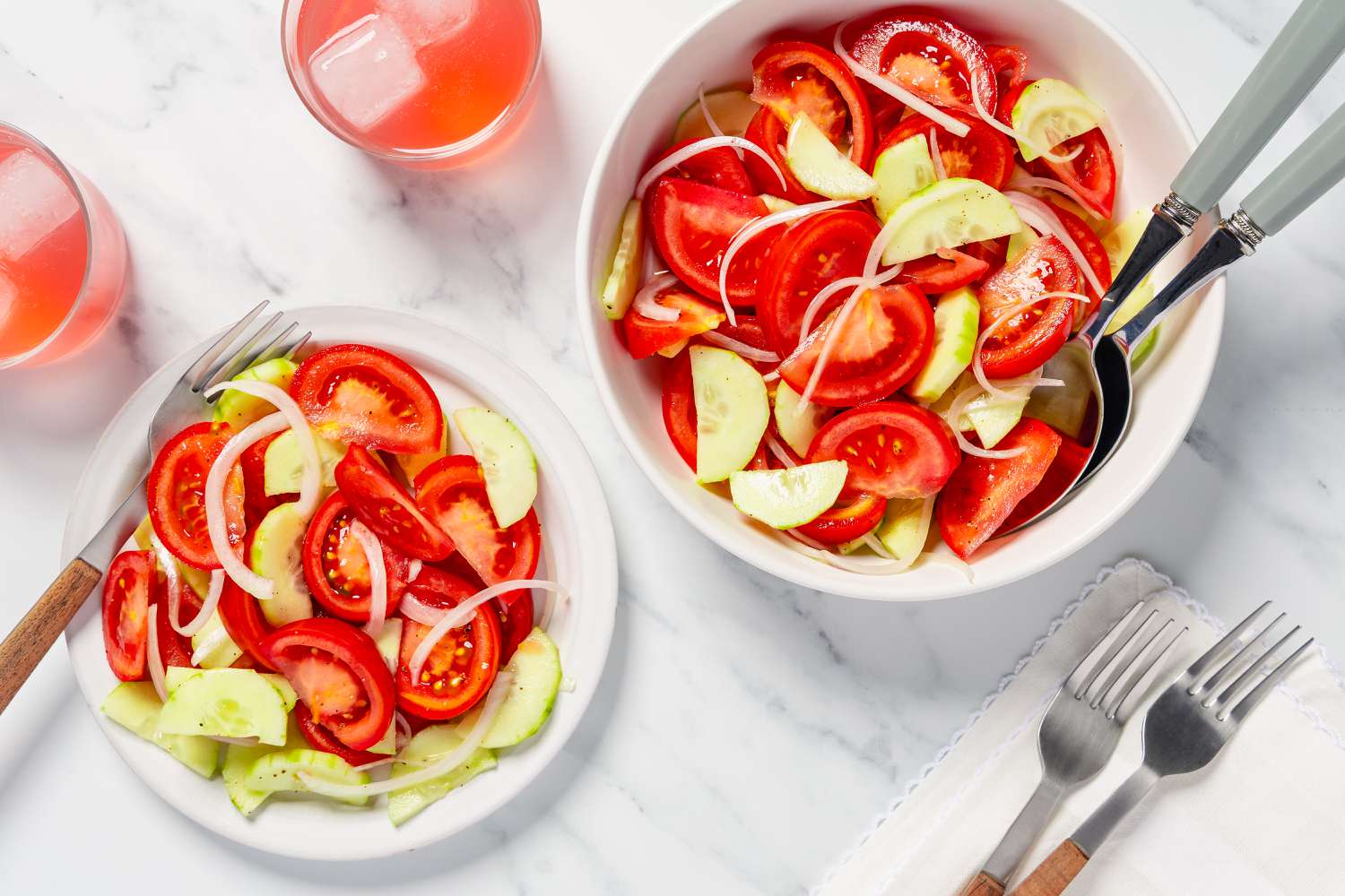 Tomato and cucumber salad served in a large bowl and a smaller plate