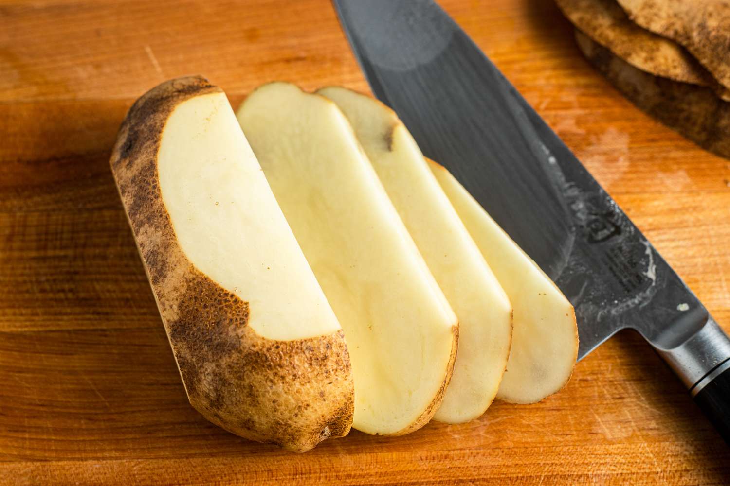 Sliced Potatoes on Cutting Board with Knife Next to It for Homemade French Fries Recipe