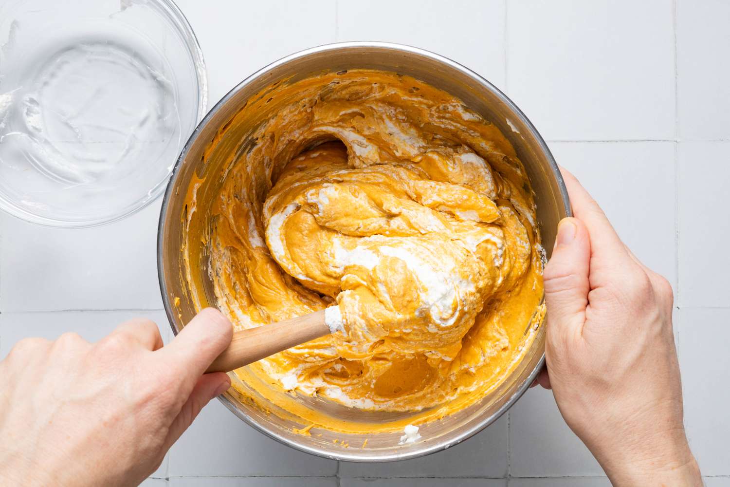 Heavy cream folded into the puree mixture using a silicone spatula for Cookie crumb, butter, and sugar blended together in a food processor for no-bake pumpkin cheesecake recipe