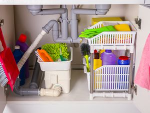 Cleaning tools and supplies in open cabinet under a kitchen sink
