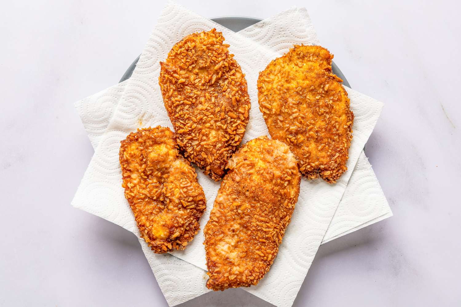 cooked pretzel chicken cutlets resting on a paper towel-lined plate for pretzel chicken recipe