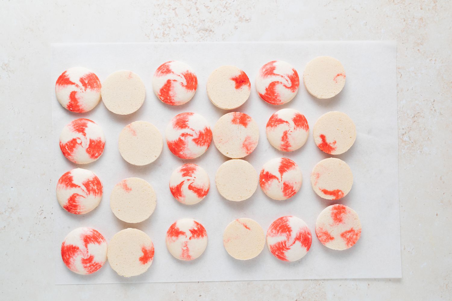 Parchment with the unfilled shells of peppermint macarons with white chocolate filling.
