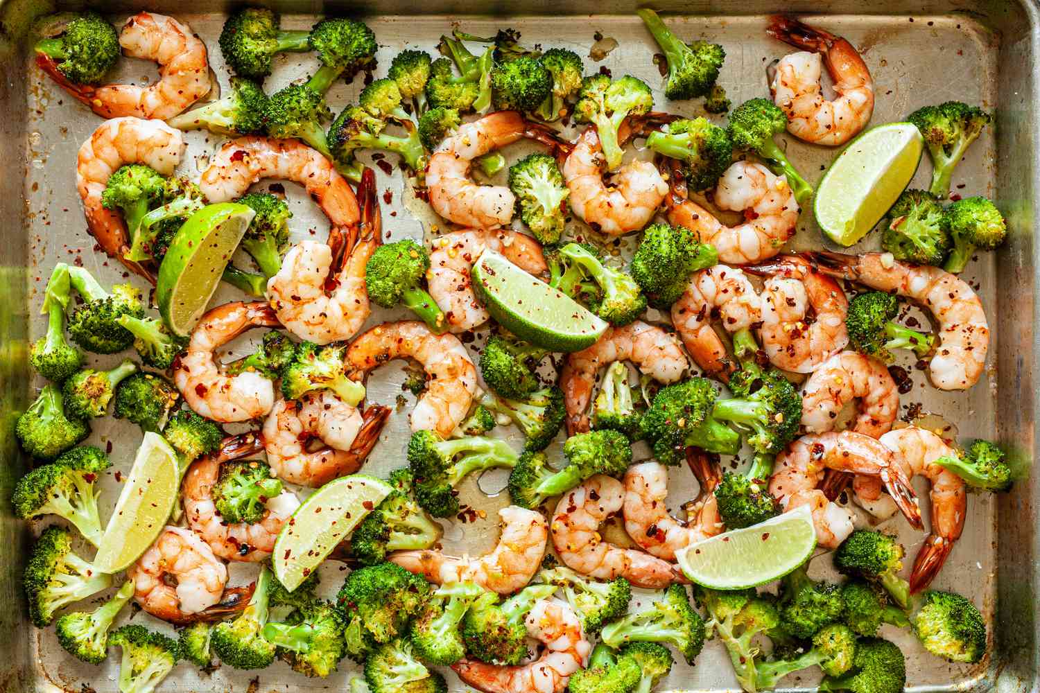 Sheet Pan Hot Honey Roasted Shrimp and Broccoli on sheet pan with limes.