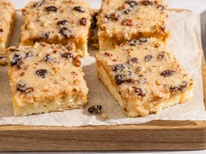 Slices of Lane cake with a fruit and nut topping on a wooden board