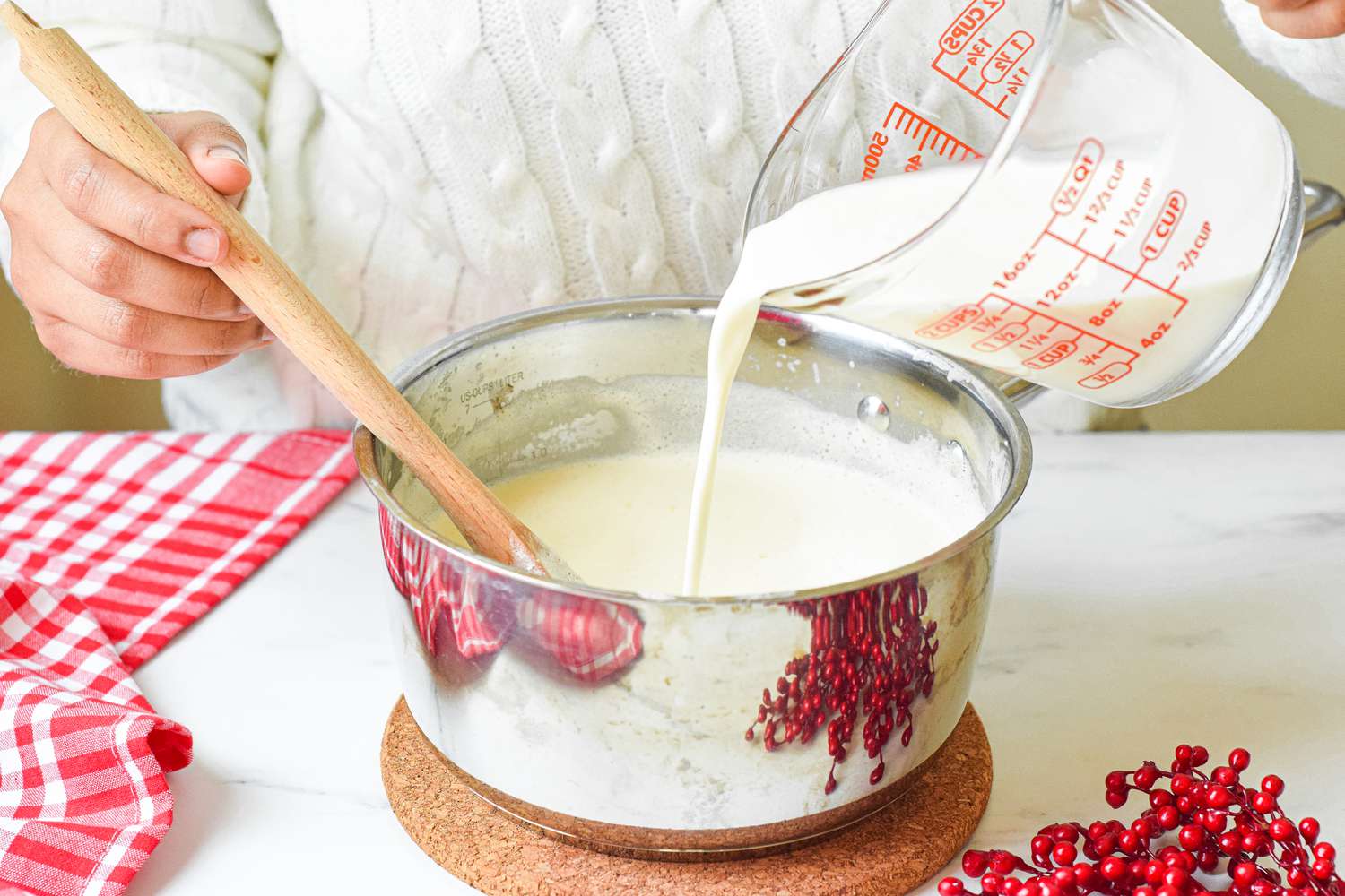 Cream being added to an eggnog mixture in a saucepan