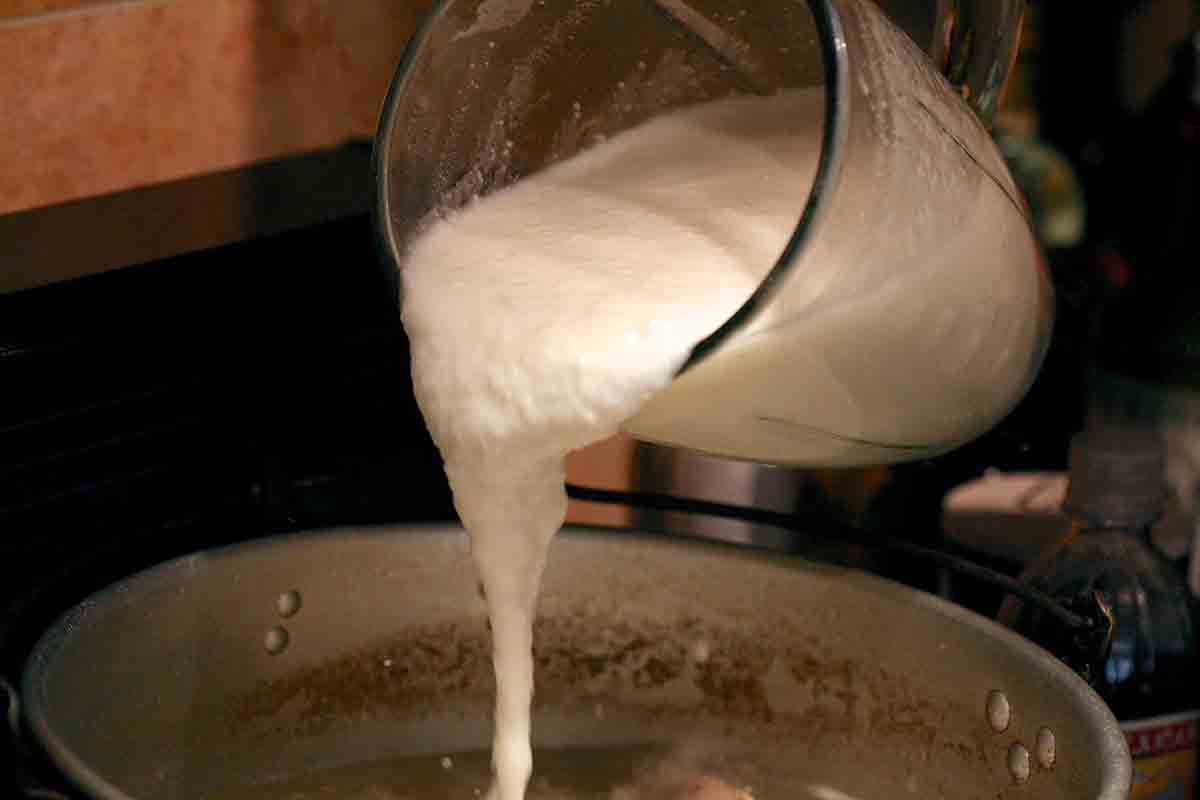 pouring blended hominy into pozole base