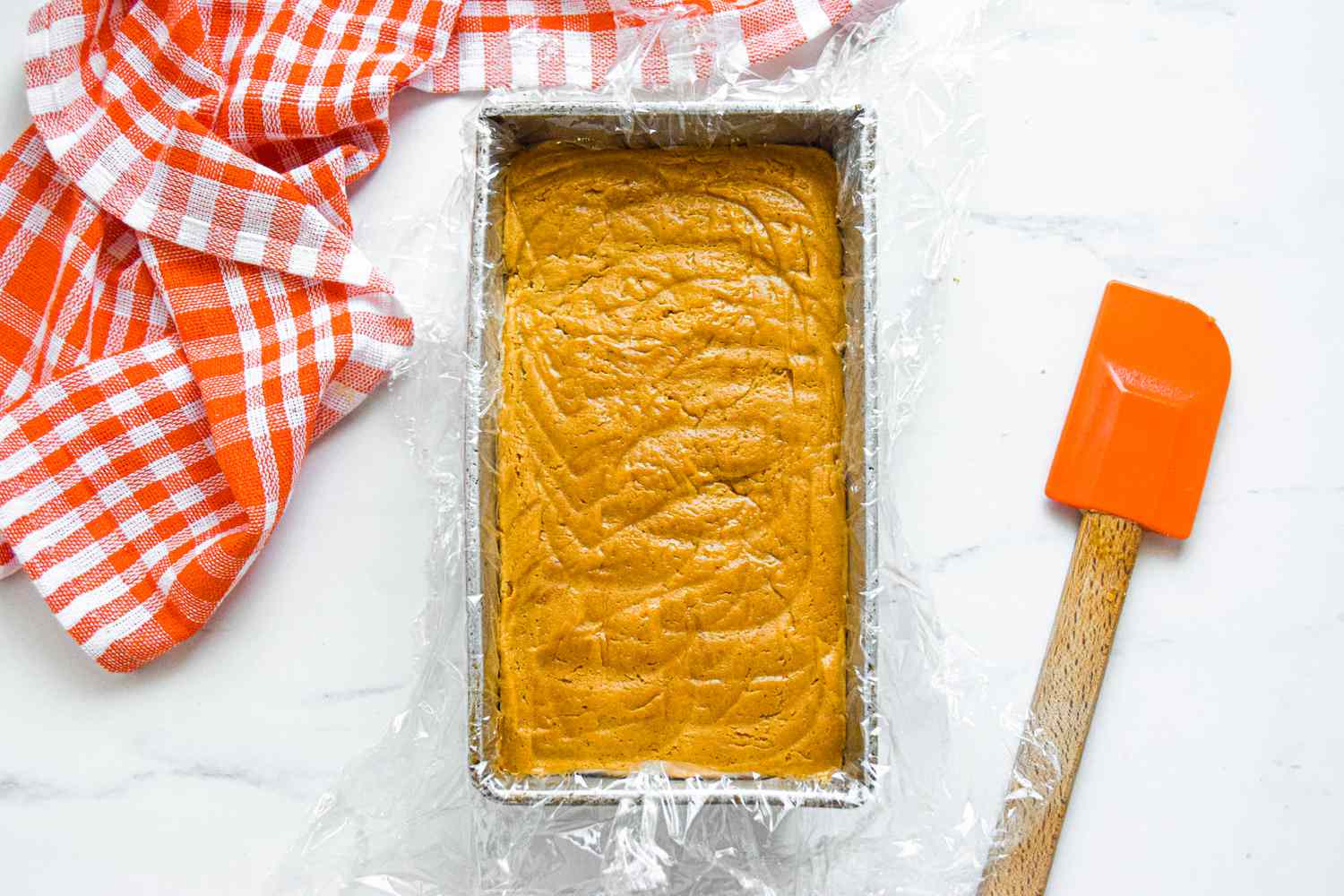Gingersnap Cookies Batter in Loaf Pan, Surrounded by Kitchen Towel and Spatula