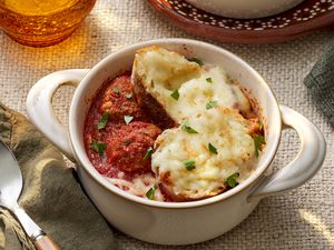 Bowl of meatball sub soup in a pot-like ramekin a rustic table setting