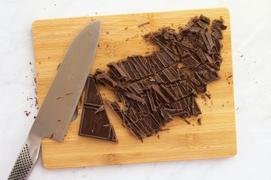Chopped chocolate and a knife on a wooden cutting board